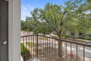 A balcony with a view of a tree and a street